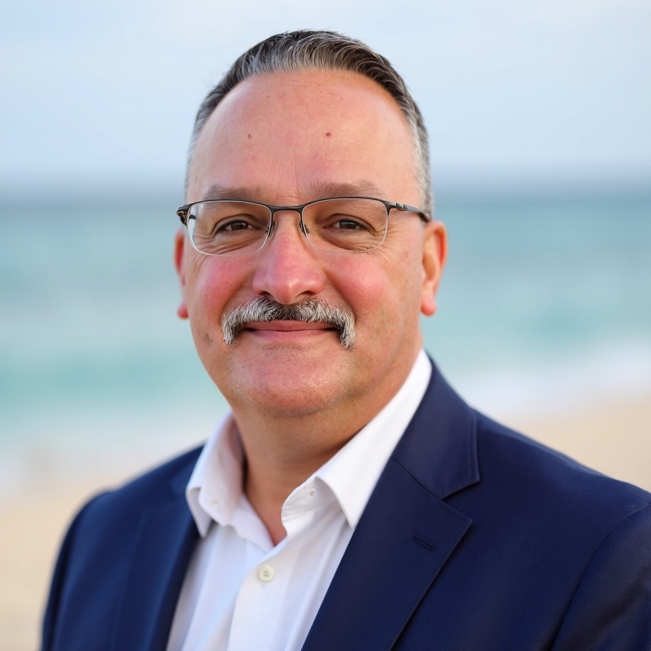 Stephen Combs wearing a navy jacket with a coastal background